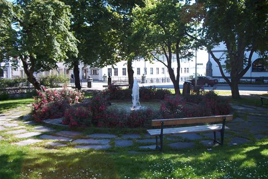 Sommer i parken. Benk og blomster foran fontene. Foto. - Klikk for stort bilde
