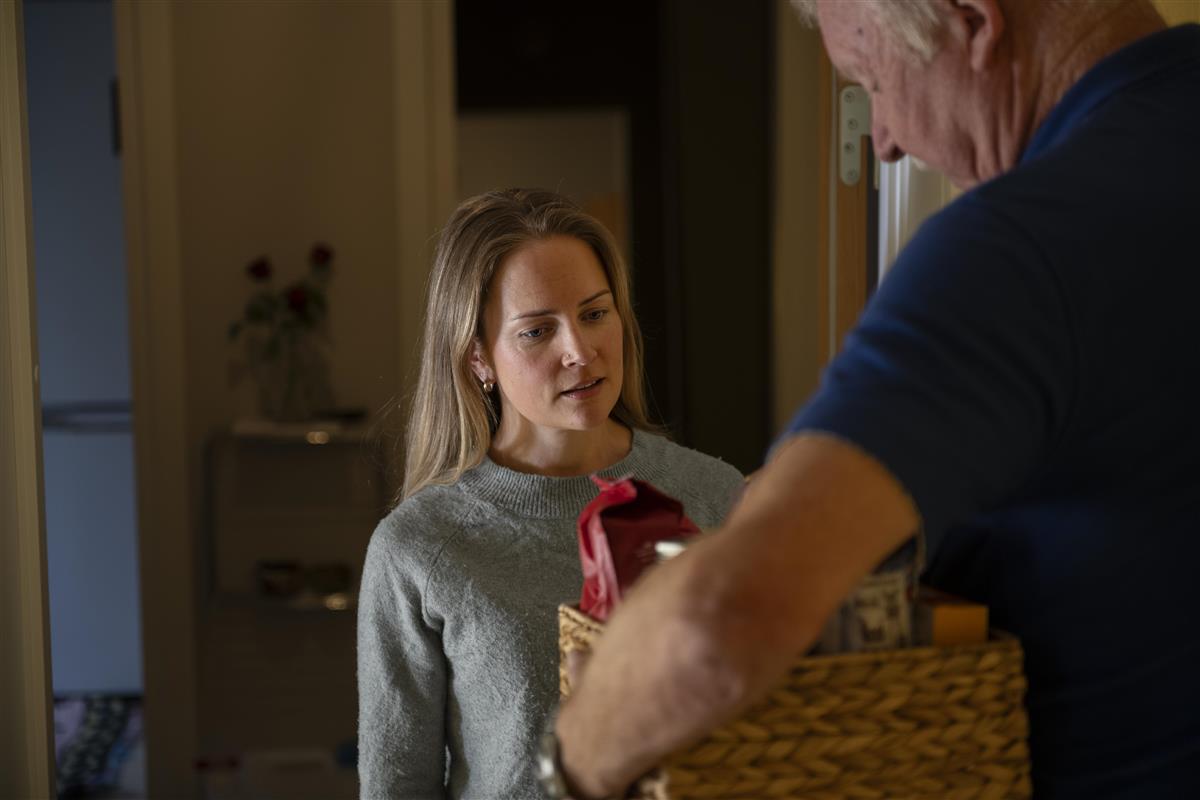 Mann gir kvinne en kurv full av matvarer. foto. - Klikk for stort bilde