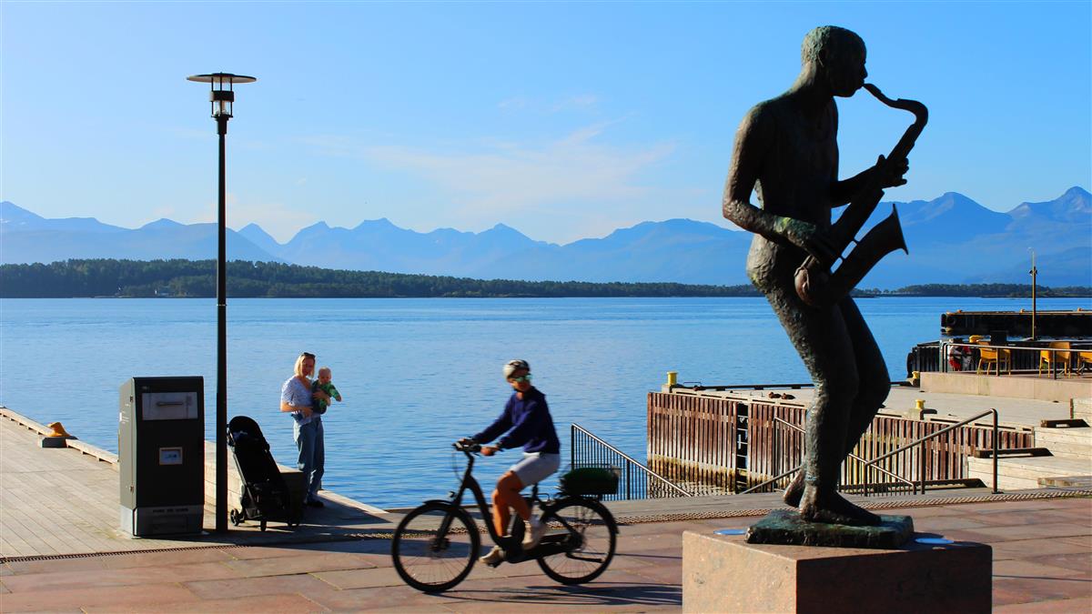 Sjøfronten med jazzmannen i forgrunnen. Foto. - Klikk for stort bilde